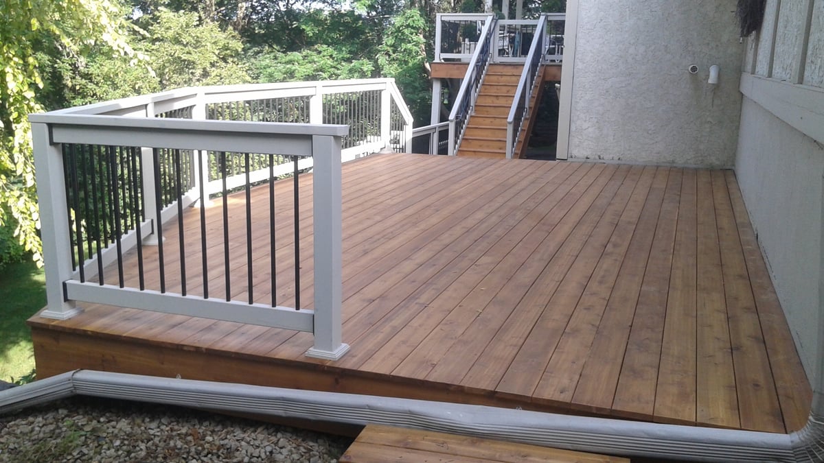 Custom cedar deck built by Minnesota carpentry company with black and white railings.